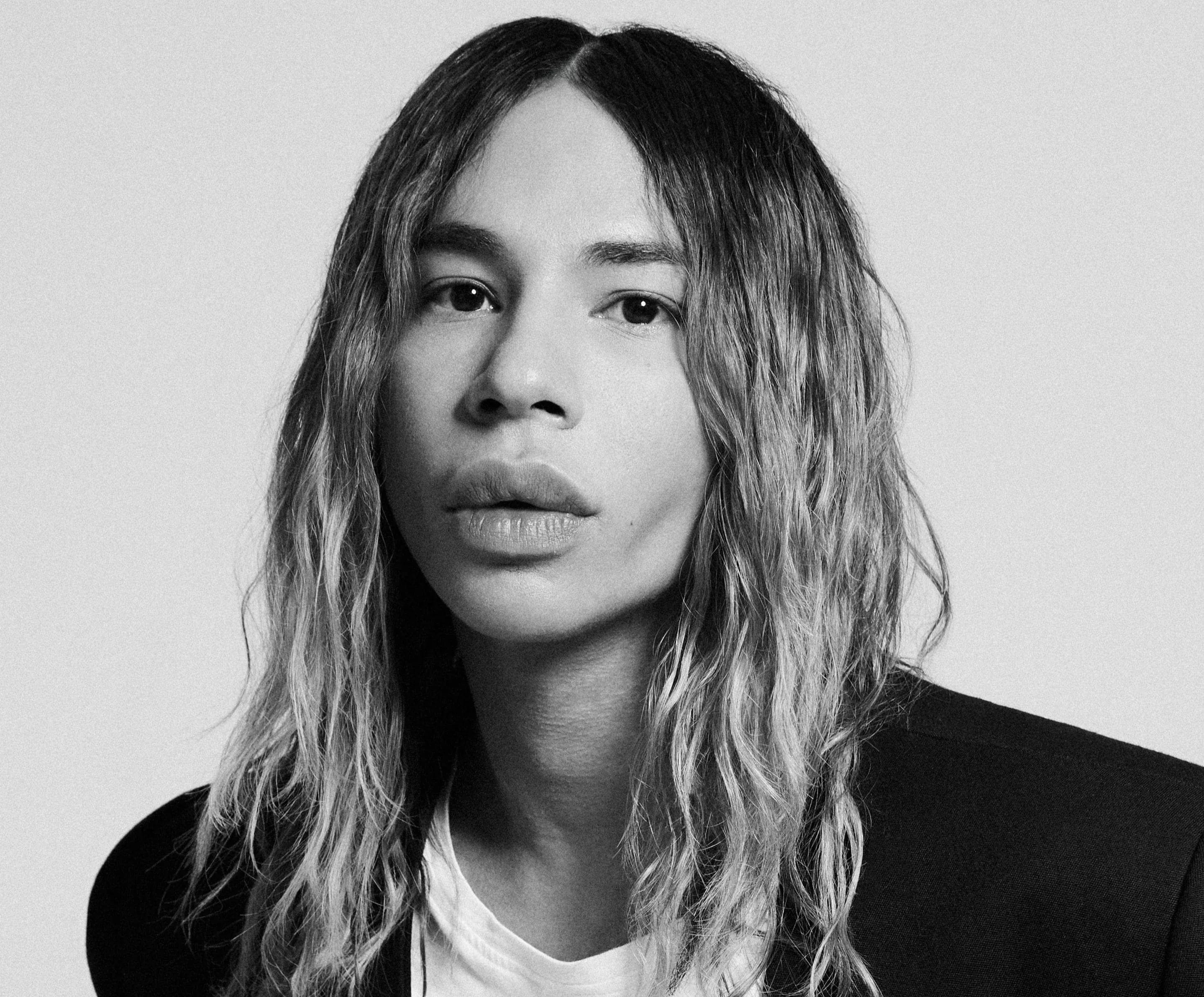 Black-and-white portrait of Olivier Rousteing, Creative Director of Rabanne, wearing a black suit and white T-shirt.
