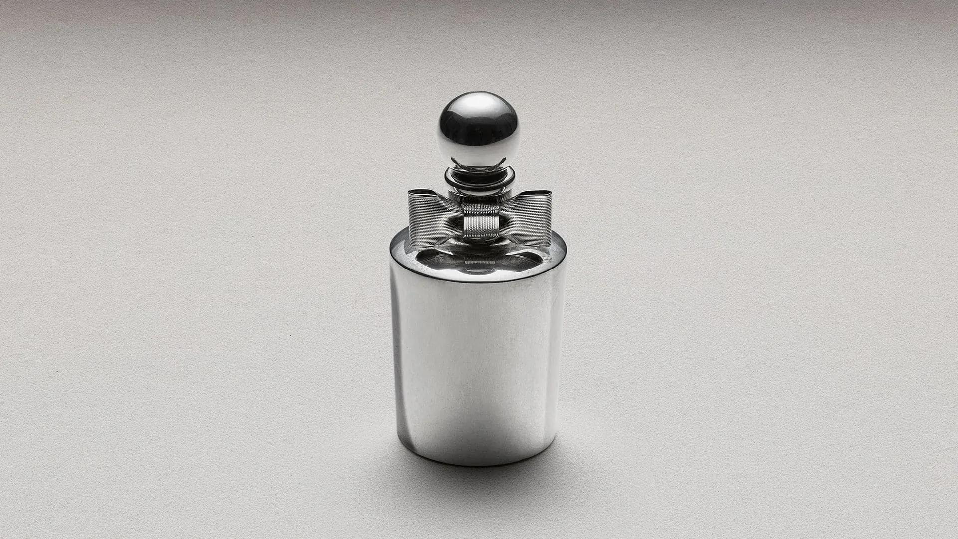 A silver perfume bottle with a rounded cap displayed against a plain light background.