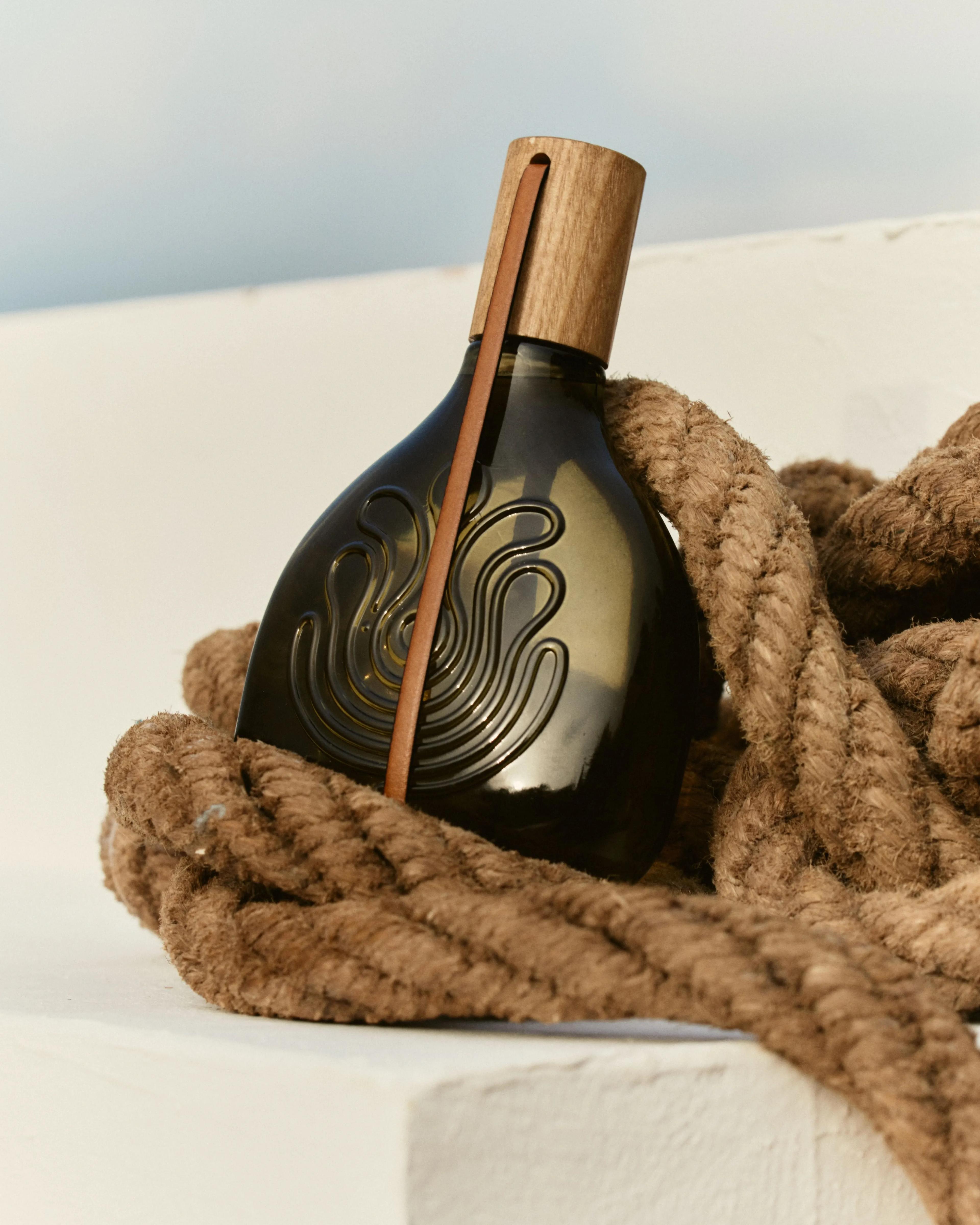 Agua Brava fragrance bottle by Puig displayed among thick rope, with a light blue background.